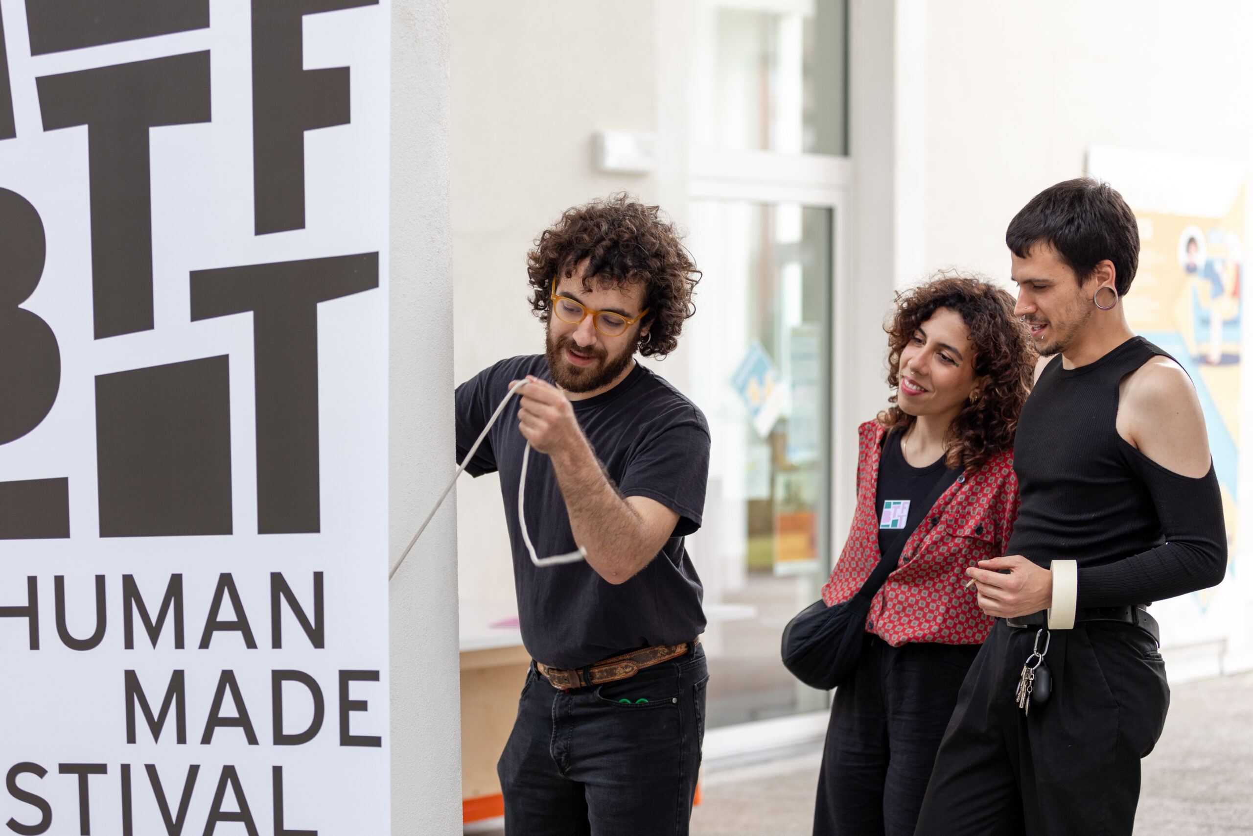 Due ragazzi e una ragazza della Direzione Artistica Partecipata Under 30 allestiscono un roll up con il logo di BTTF e il claim “Human Made Festival”.