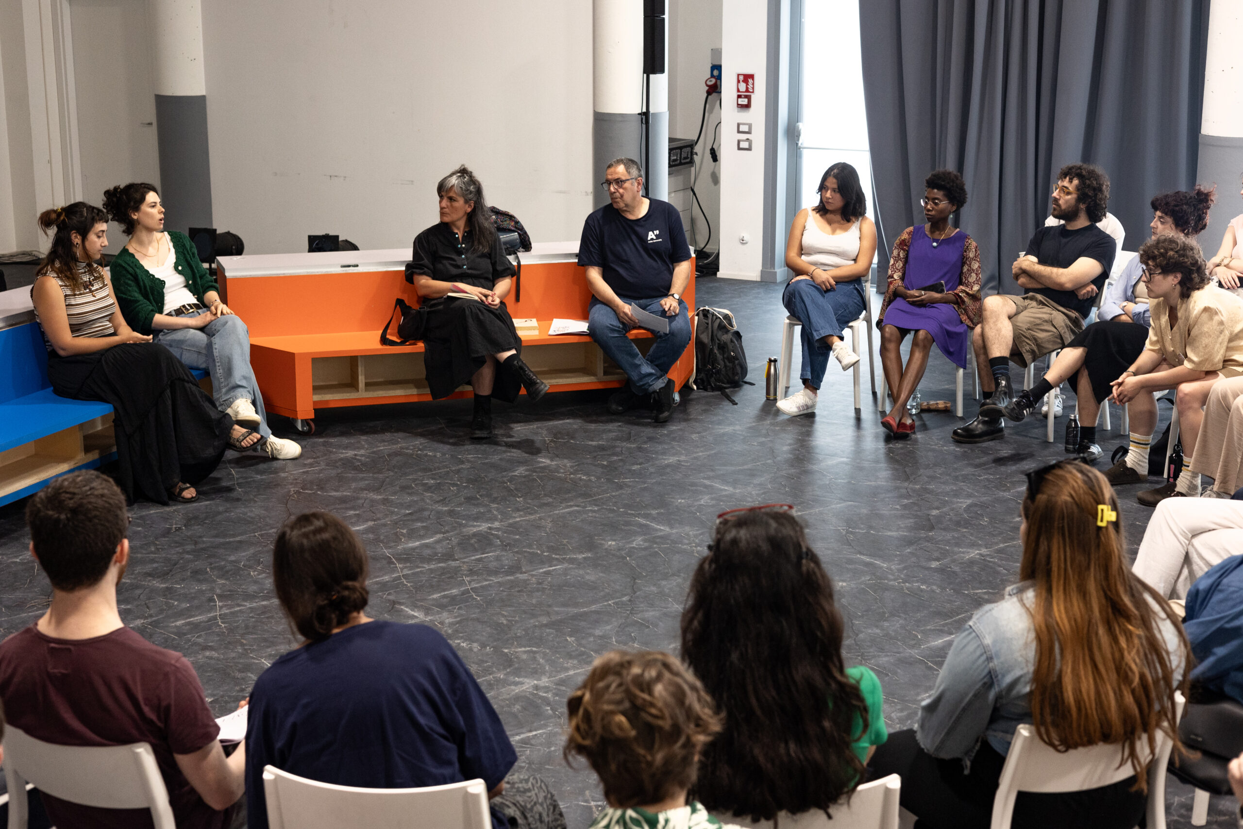 Alcune persone sedute in cerchio partecipano al laboratorio “Esercizi di immaginazione collettiva”.