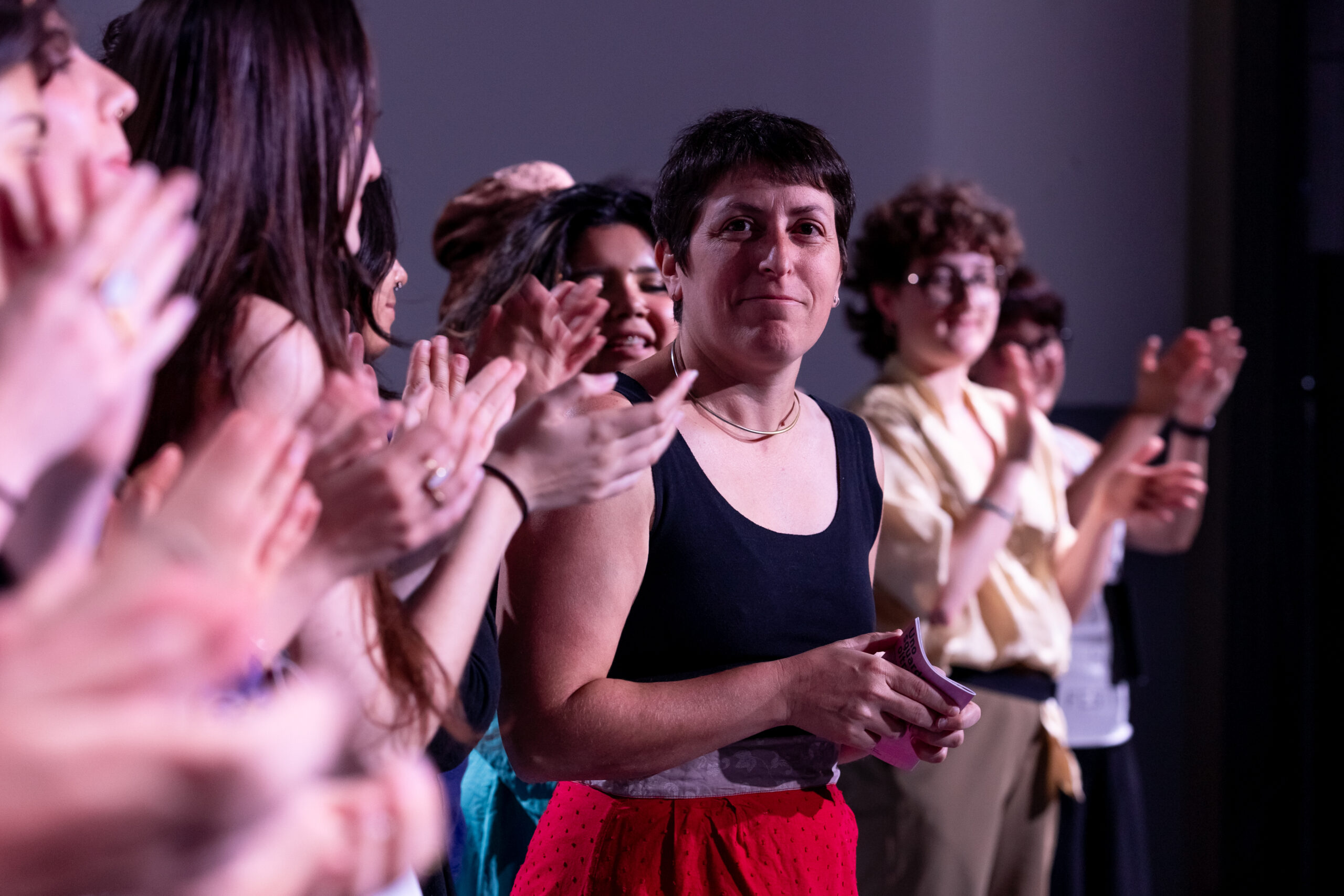 Una donna dello staff ripresa mentre applaude con un gruppo di ragazze e di ragazzi della Direzione Artistica Partecipata Under 30.