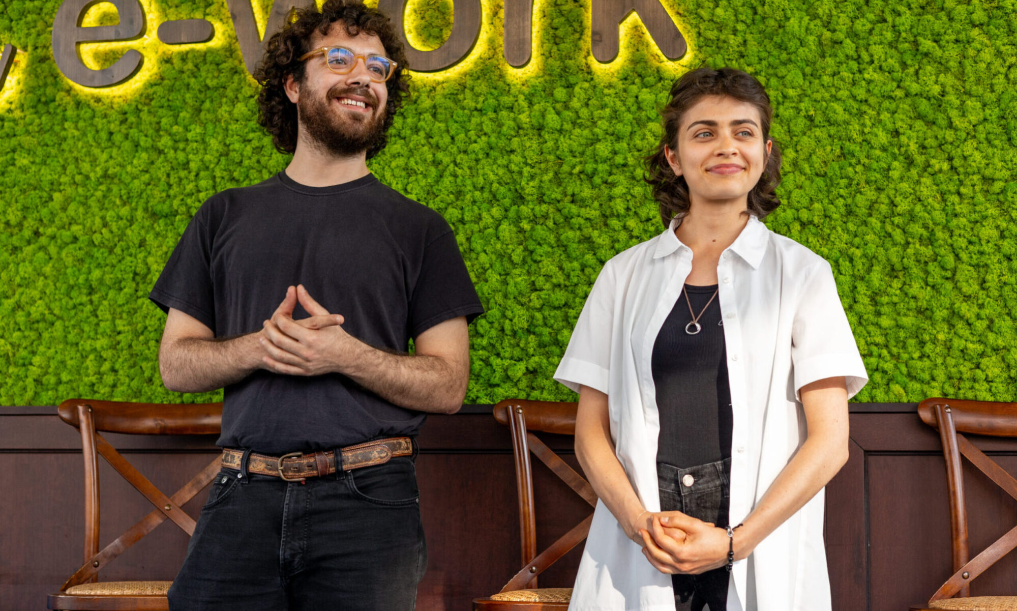 Un ragazzo con la barba e capelli ricci scuri e una ragazza con i capelli corti parlano e sorridono, raccontando il festival.