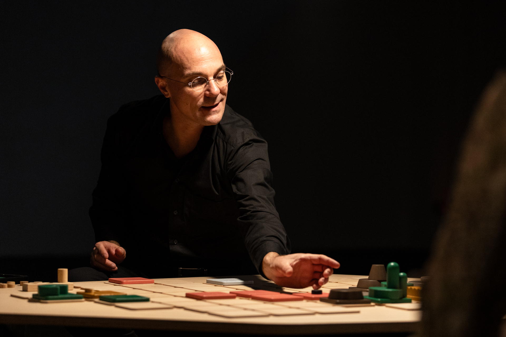 Il performer di “Eutopia” sta per muovere una pedina sul tavolo da gioco che rappresenta un ecosistema.