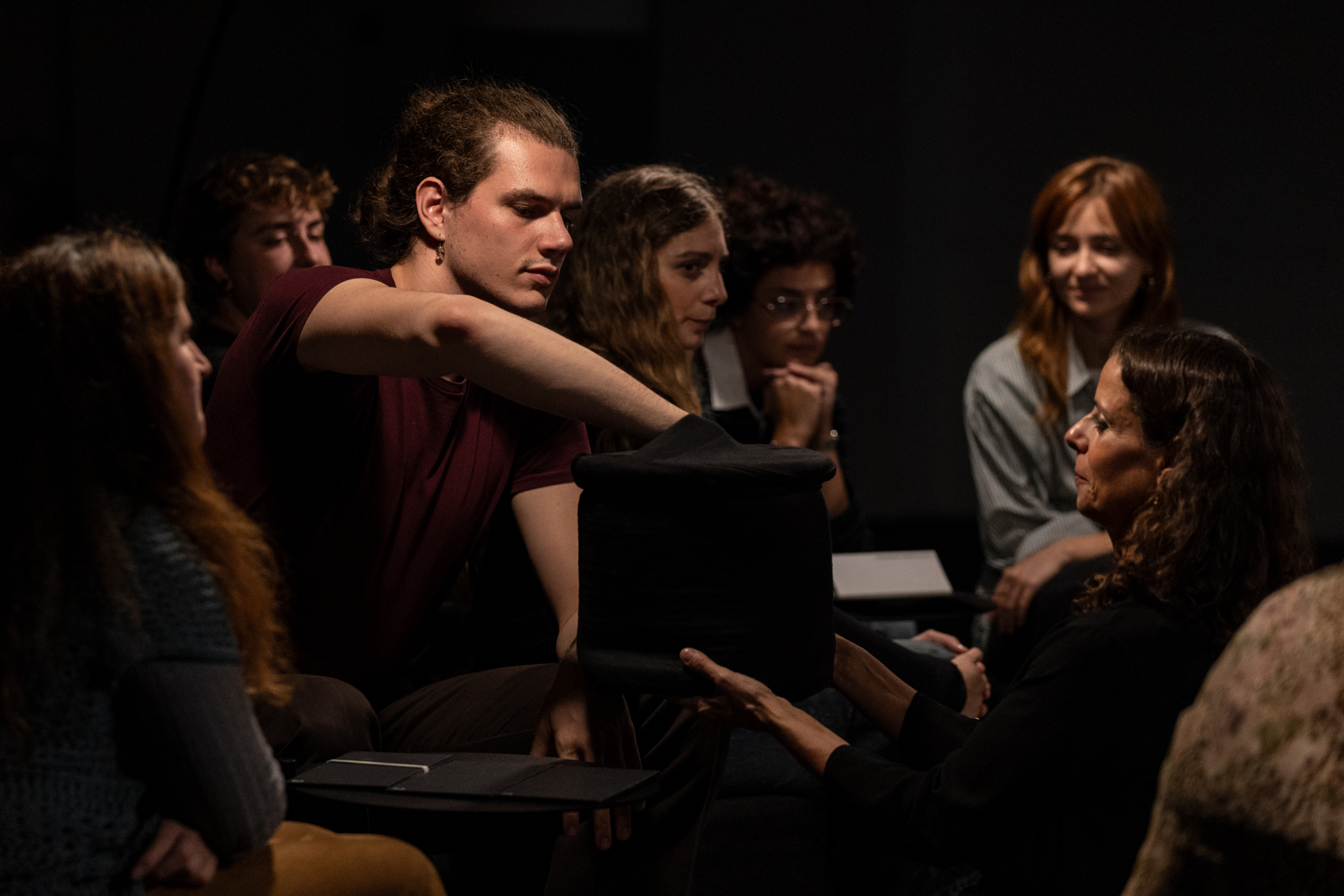 Durante la performance "Eutopia", la performer inginocchiata porge al pubblico un sacchetto scuro e un ragazzo pesca qualcosa al suo interno