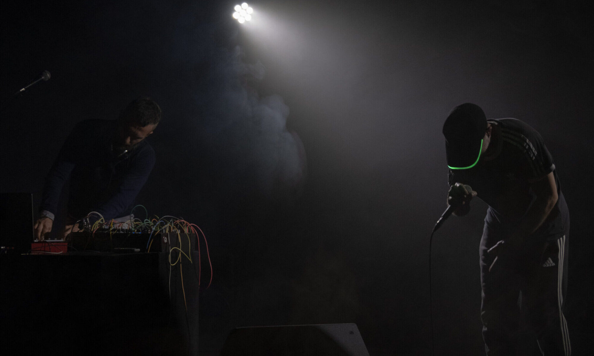 In una scena molto scura si intravedono un dj e un narratore