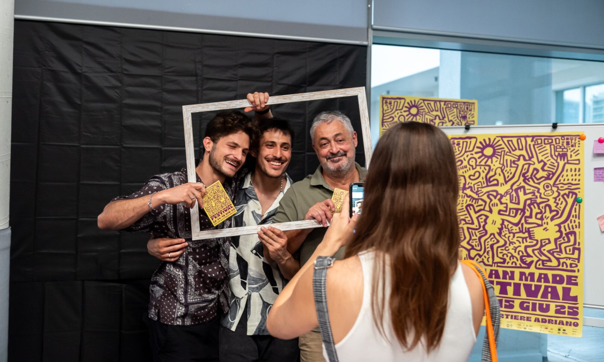 Un gruppo di tre uomini di diverse età si fa fotografare in una cornice da una giovane donna